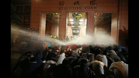 Protesters are sprayed with a water cannon during a demonstration outside the Executive Yuan building in Taipei on March 24.