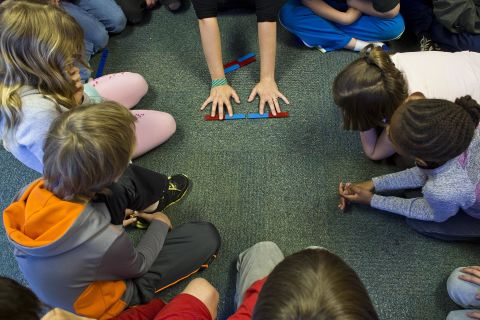 Students learn about the properties of magnets while sitting in a circle on the floor. Hess Academy students are encouraged to move as much as they need while doing their classwork.