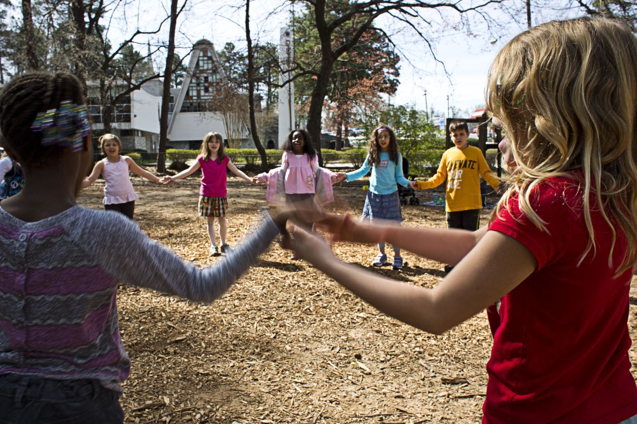 Students join hands while playing a game outside. Many days begin and end on the school's playground.
