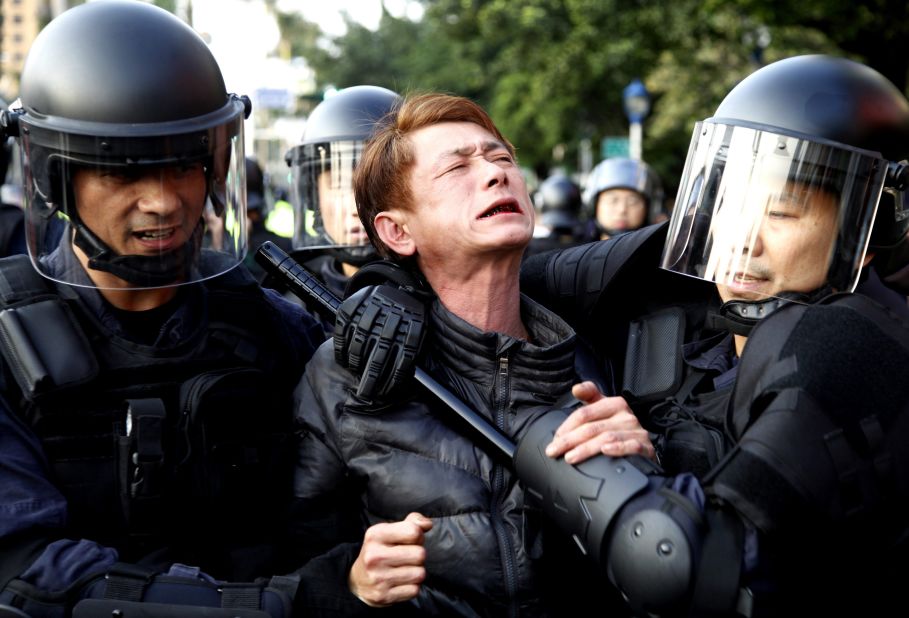 Riot police detain a protester near the Cabinet compound on March 24.