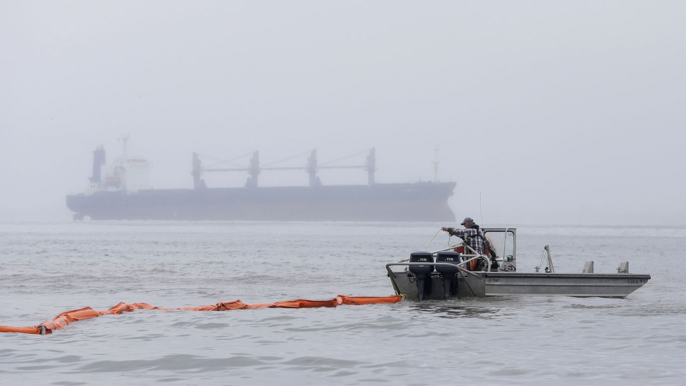 A boat drags an oil boom out into the water along East Beach on March 24.