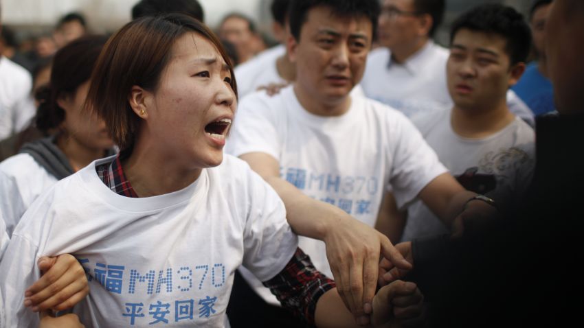 A relative of passengers on missing Malaysia Airlines flight MH370 yells at a security personnel while she attends a protest outside the Malaysian embassy in Beijing on March 25, 2014.