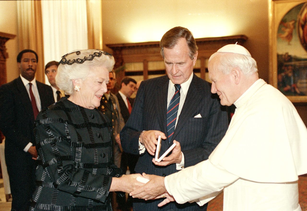 El papa Juan Pablo II le entrega a la primera dama Bárbara Bush la medalla del Vaticano ante la mirada del presidente George H.W. Bush durante una ceremonia en el Vaticano en 1989.