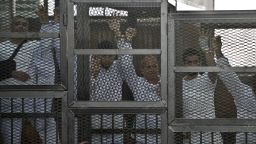 Australian journalist Peter Greste (C) of Al-Jazeera and his colleagues stand inside the defendants cage during their trial for allegedly supporting the Muslim Brotherhood at Cairo's Tora prison on March 5, 2014.