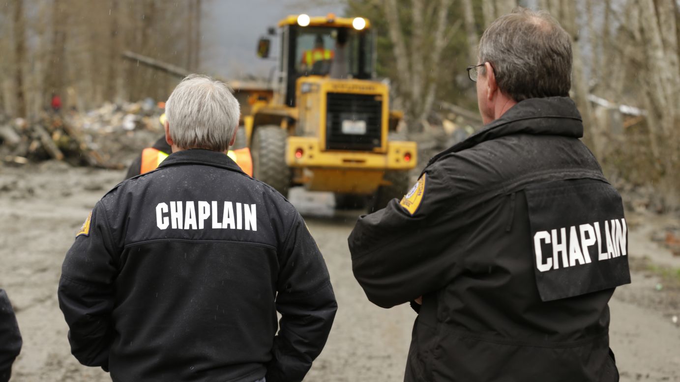 Chaplains watch as crews clear debris from State Route 530 in Oso on March 25.