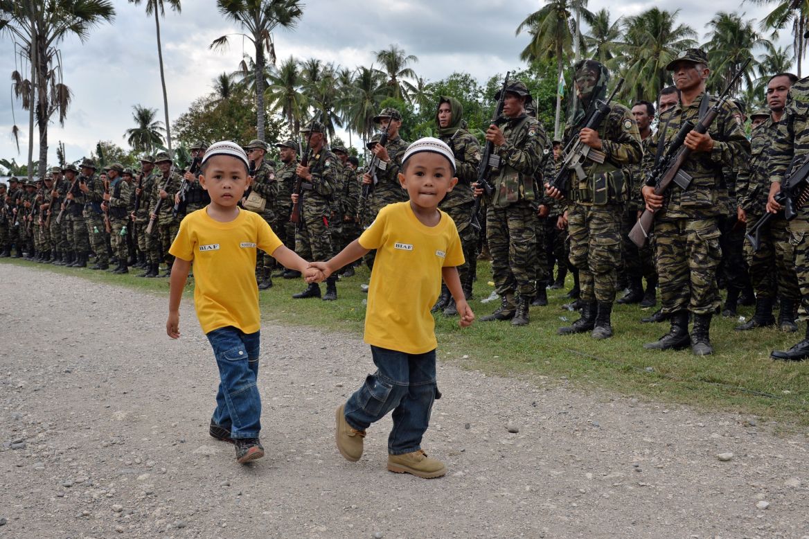 MARCH 27 - SULTAN KUDARAT, PHILIPPINES: Two boys walk past Moro Islamic Liberation Front rebels during a rally in support of the peace agreement on the southern Philippine island of Mindanao. The biggest Muslim rebel group in the country signed the historic pact, ending one of Asia's longest and deadliest conflicts.