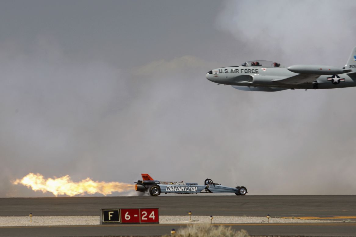 A Lockheed T-33 Shooting Star flies past the Smoke-N-Thunder jet car during a race between the two at the Los Angeles County Air Show on Friday, March 21.
