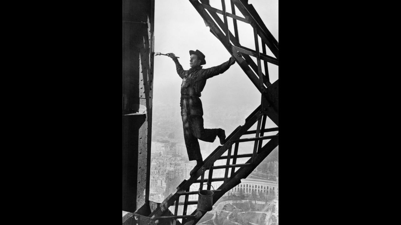 A man named Zazou paints the Eiffel Tower in 1953. The tower is repainted every seven years, necessitating 60 metric tons of paint. 
