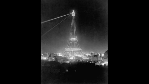 Spotlights illuminate the Eiffel Tower during the 1900 Universal Exposition.
