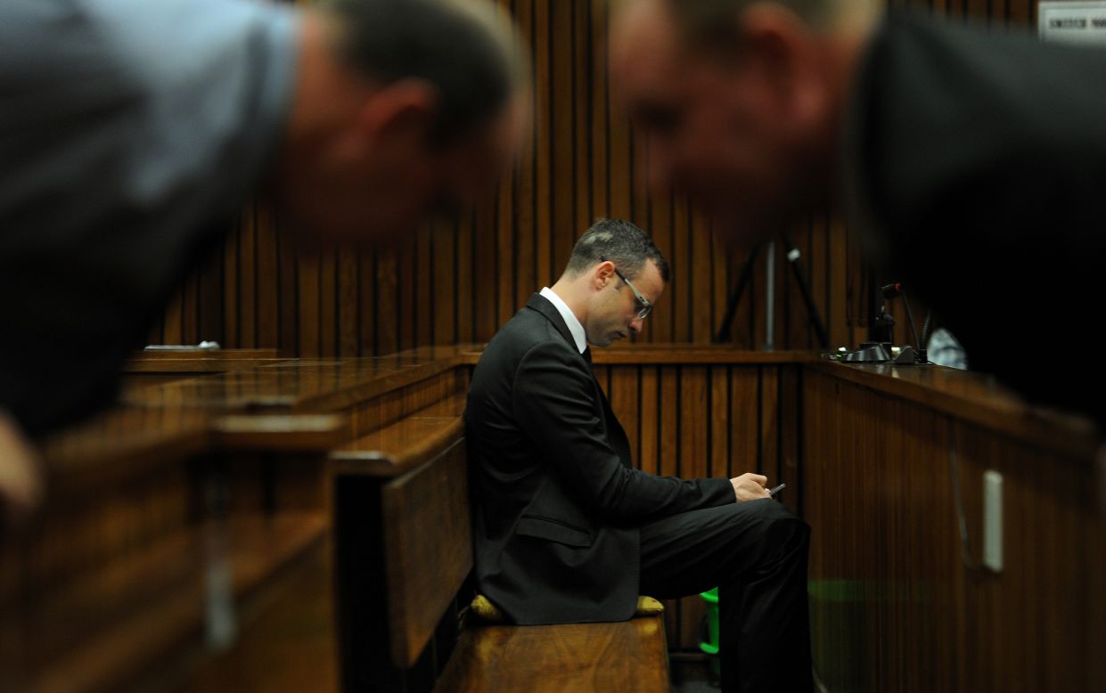 Pistorius sits inside the courtroom as members of his defense team talk in the foreground Friday, March 28.