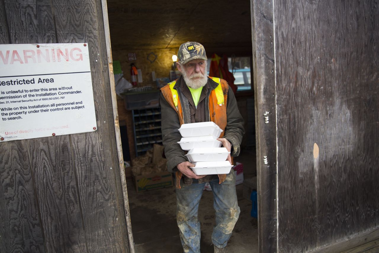 Skaglund Quarry worker Warren Tollenaar carries meals donated by concerned community members. He is among the workers who are grinding up rock so trucks and rescue equipment can get through the landslide debris zone. He, like all of the volunteers, aren't getting paid. They do it, he says, because that's what has to be done.