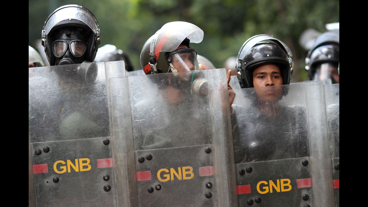 Officers stand guard during an anti-government march in Caracas on Saturday, March 29.
