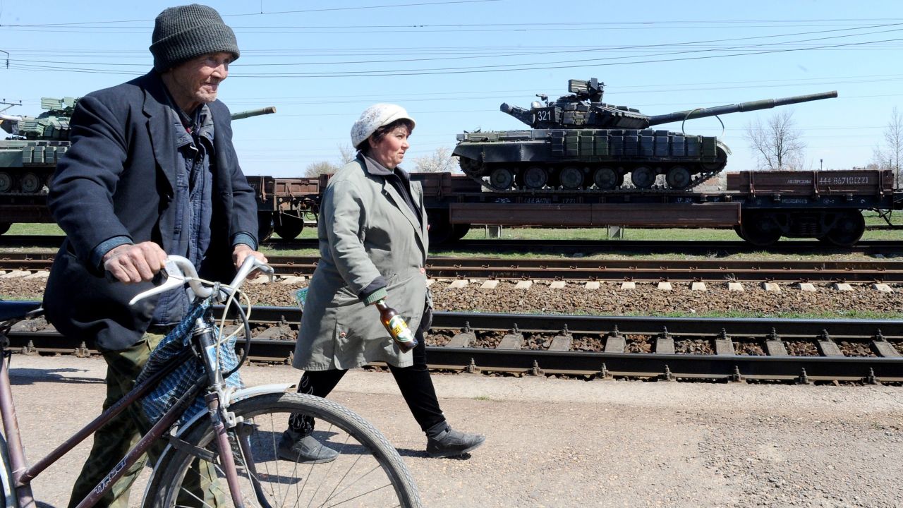 People walk past a train loaded with Russian tanks Monday, March 31, in the Gvardeyskoe railway station near Simferopol, Crimea.
