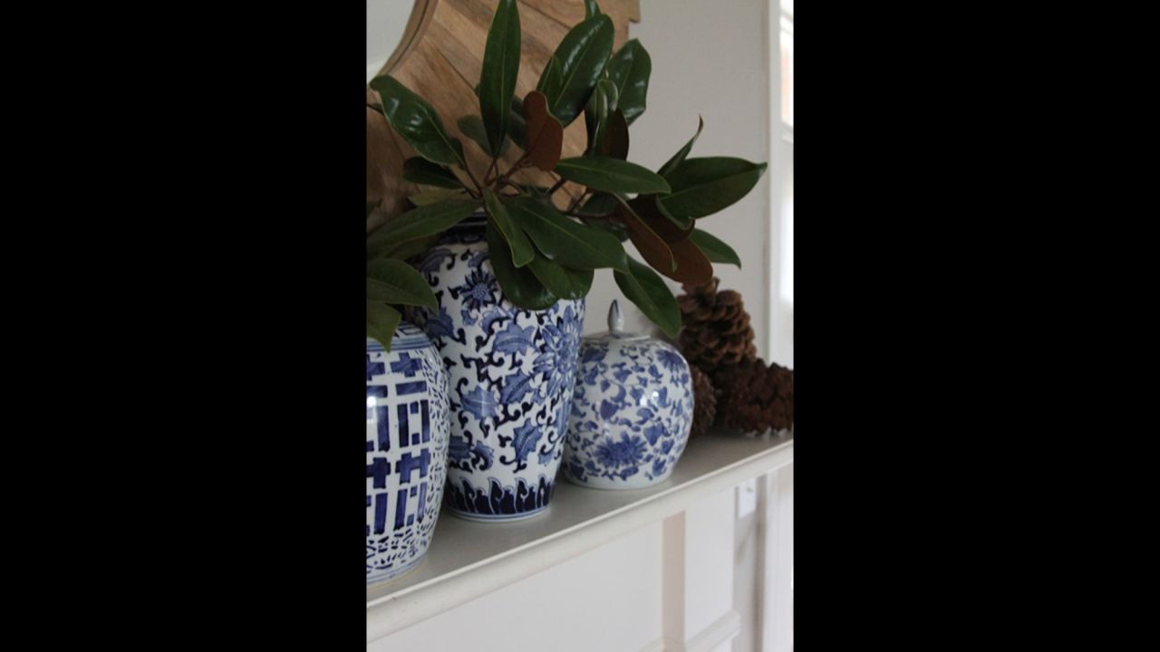 Blue chinoiserie ginger jars are a recent evolution of Clark's love of blue decor. Magnolia branches and pine cones in addition to the jars bring organic texture to her mantle.