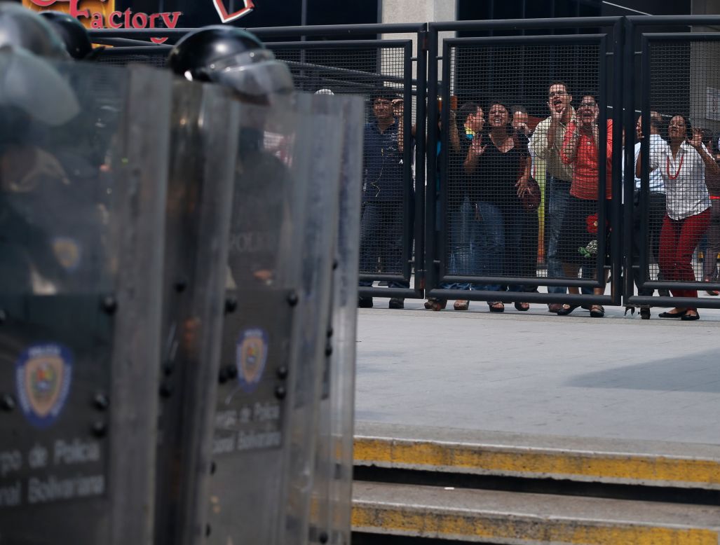 People shout insults at police Tuesday, April 1, during clashes between police and anti-government protesters in Caracas.