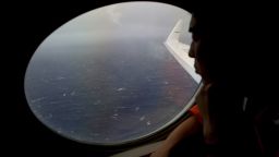 Koji Kubota of the Japan Coast Guard keeps watch through a window of their Gulfstream V aircraft while flying in the search zone for debris from the missing Malaysia Airlines flight MH370 Tuesday, April 1, 2014 off Perth, Australia.