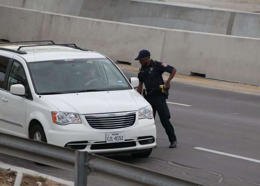 A police officer checks drivers' IDs outside the main gate at Fort Hood.