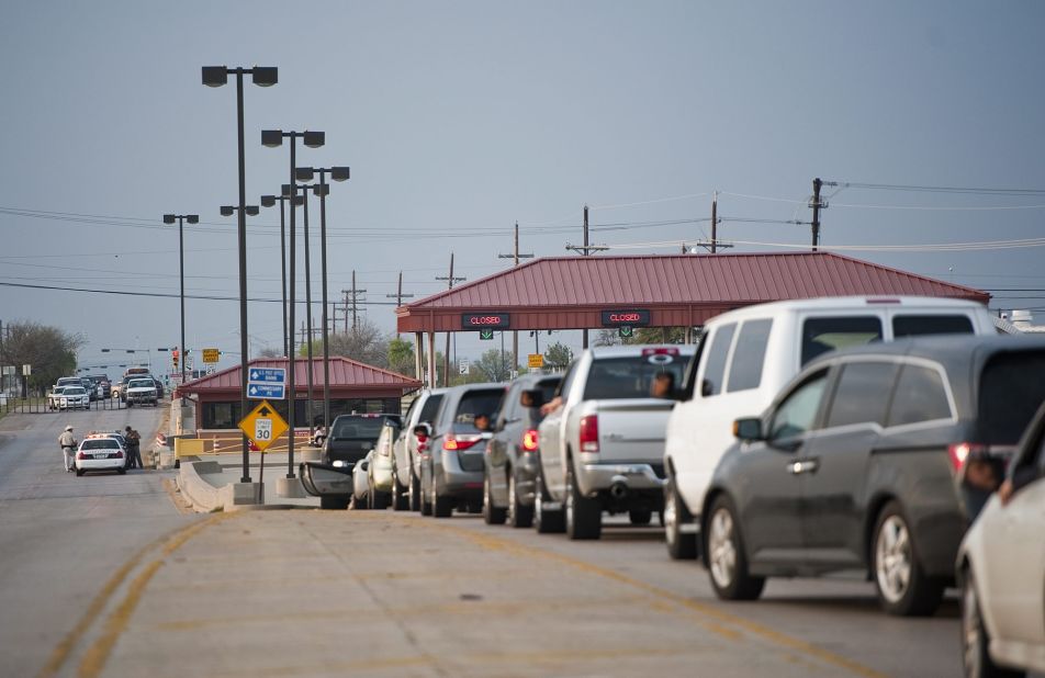 Vehicles wait at a closed entrance to Fort Hood.