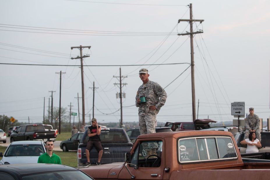 Military personnel and civilians wait outside Fort Hood for updates on the situation.