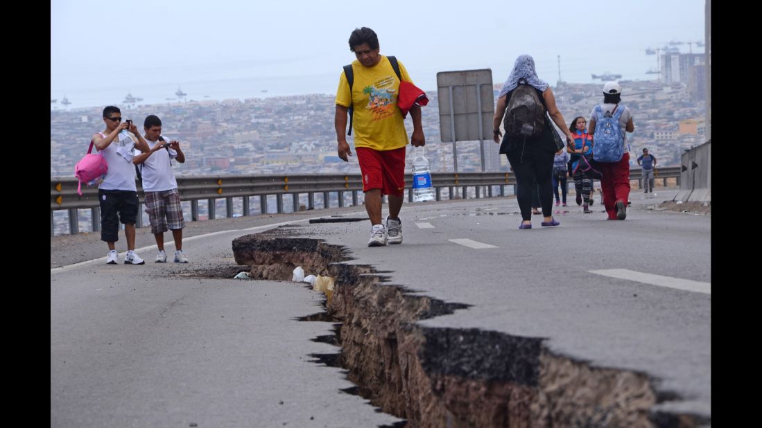 People walk along a cracked road in Iquique on Wednesday, April 2.