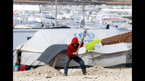 A boy uses a tool to dig a hole at the Zaatari refugee camp in northern Jordan on Saturday, March 15.