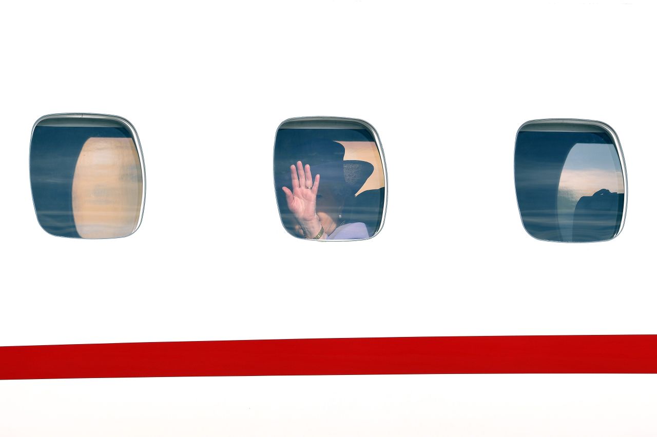 The Queen waves goodbye through an airplane window at Ciampino airport.