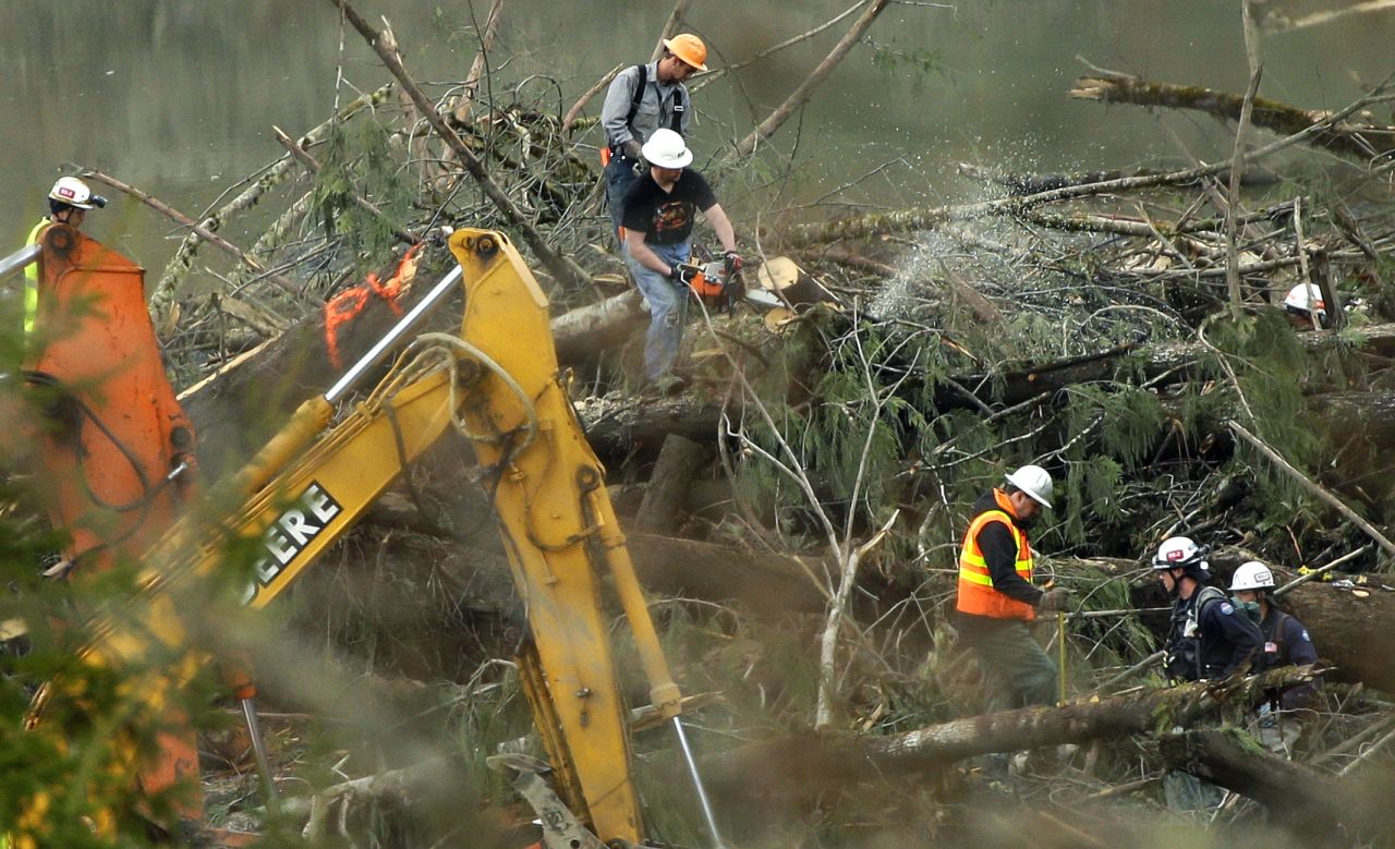 Workers cut a tree next to a possible victim on Sunday, March 30.