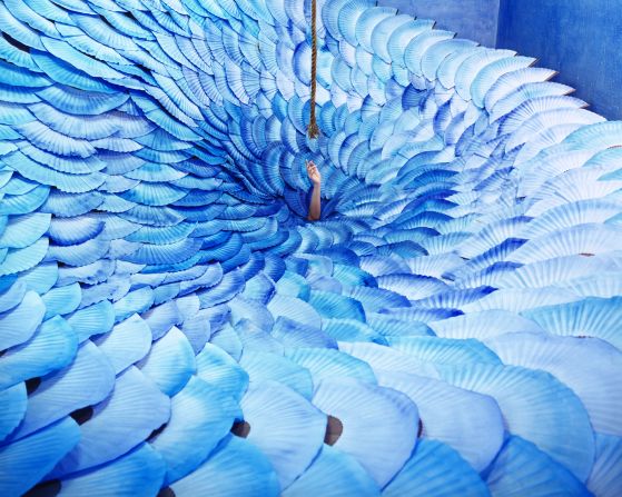 In this photo, traditional Korean painted fans are arranged to resemble a whirlpool out of which a hand reaches for the rope above. Inspired by the Korean fairy tale of the Sun and the Moon, it portrays a person reaching out for a silver lining. 