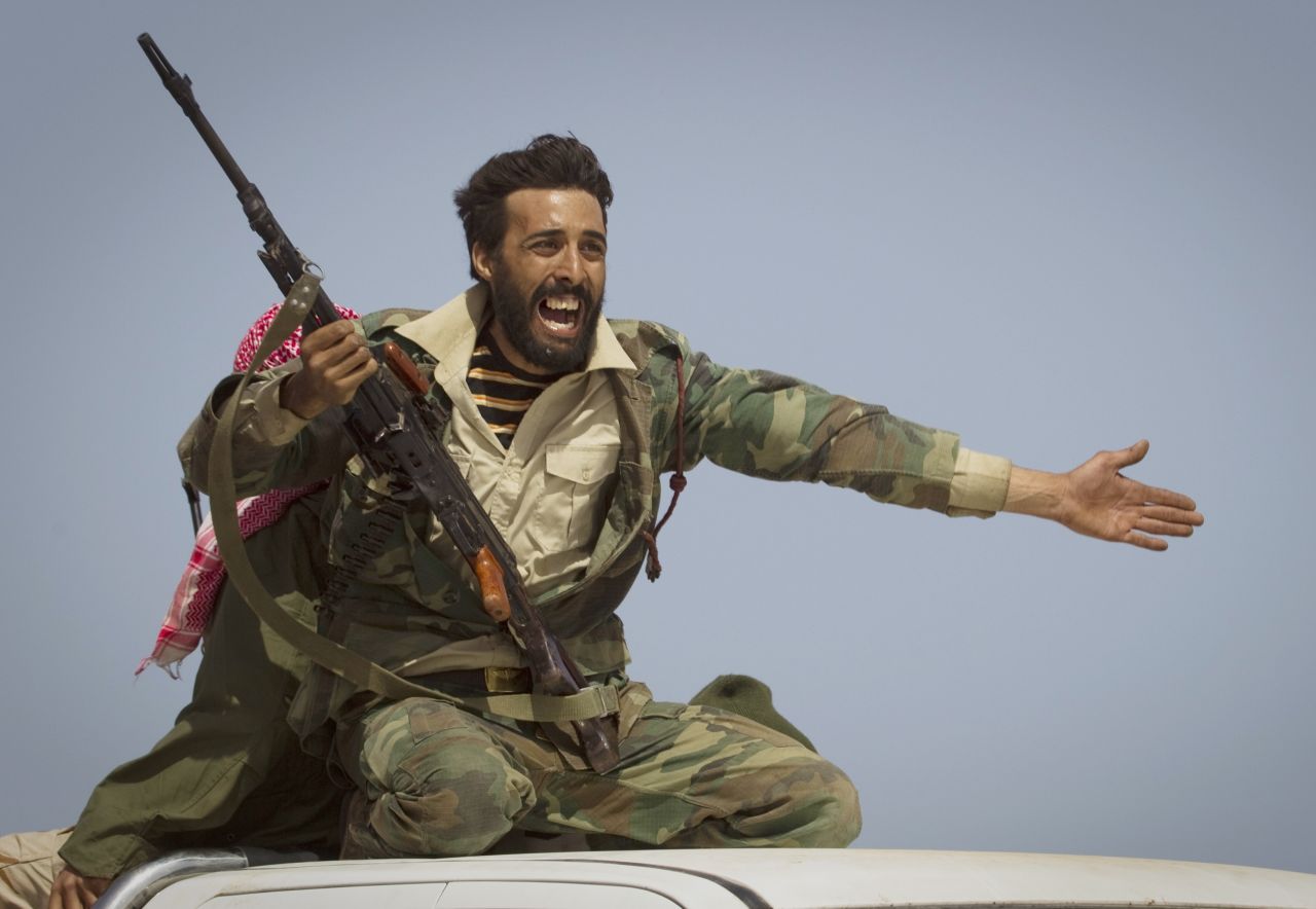 A Libyan rebel urges people to leave as shelling from Moammar Gadhafi's forces started landing outside of Bin Jawad, Libya, in March 2011.