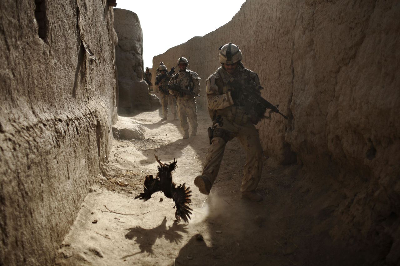 A Canadian soldier chases a chicken seconds before he and his unit were attacked by grenades during a patrol in Salavat, Afghanistan, in September 2010.