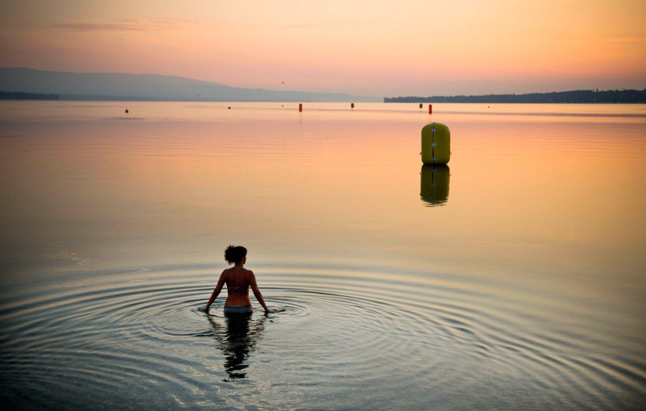 A woman in Geneva, Switzerland, takes a dip in Lake Geneva during a sunrise in July.
