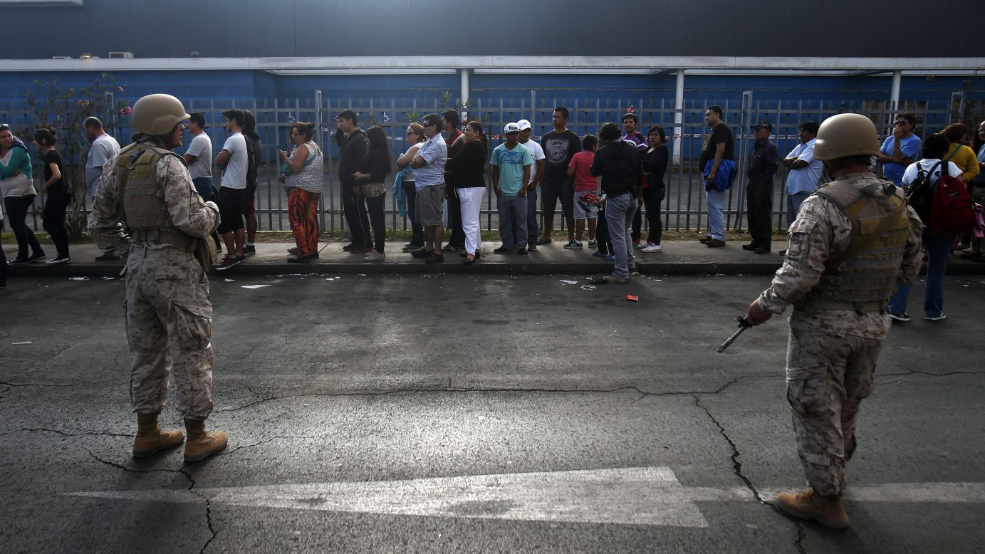 Chilean soldiers stand guard at a supermarket as people wait in line to buy supplies in Iquique, Chile, on April 3.