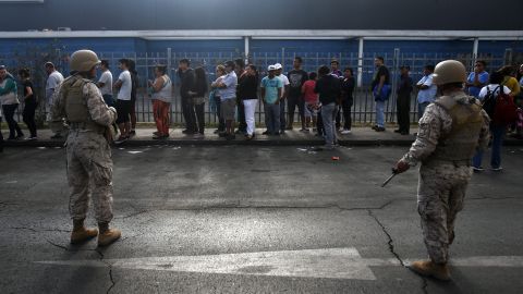 Chilean soldiers stand guard at a supermarket as people wait in line to buy supplies in Iquique, Chile, on April 3.