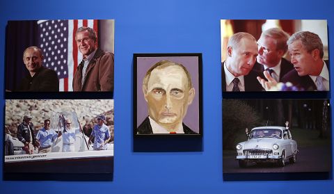 A portrait of Russian President Vladimir Putin, painted by George W. Bush, is displayed between photographs as part of the library's exhibit "The Art of Leadership: A President's Personal Diplomacy." The exhibit includes more than two dozen never-before-seen portraits by Bush.