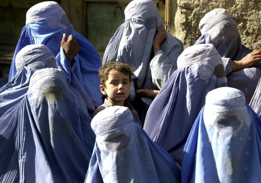  A young boy stands among a group of veiled women waiting to receive food aid during a U.N. World Food Program distribution in Kabul in November 2001. "I myself remember the mujahideen's takeover of Kabul on 27 April 1992," says Mosadiq. "On 26 April I wore a miniskirt and a sleeveless shirt, but the day after I was terrified to walk outside without being fully covered."  