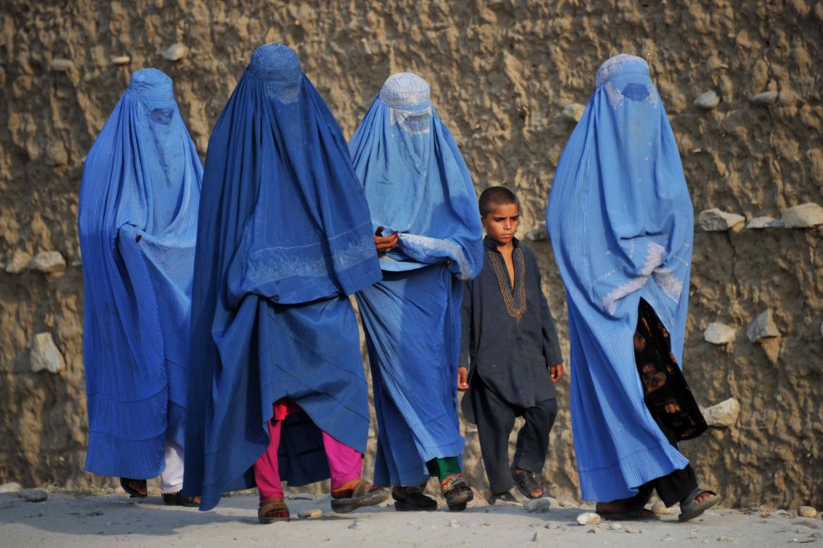 Covered from head to toe, women walk on the outskirts of Jalalabad, accompanied by a liberally-dressed boy, in October 2013. Horia Mosadiq, Amnesty International's Afghanistan Researcher, says that although there are not any legal restrictions on women's dress code in Afghanistan, considerable social and cultural pressures force them to wear a burqa or fully cover themselves. "They would simply be targeted otherwise," she says, "by the Taliban, their family members, or even passers-by on the street."