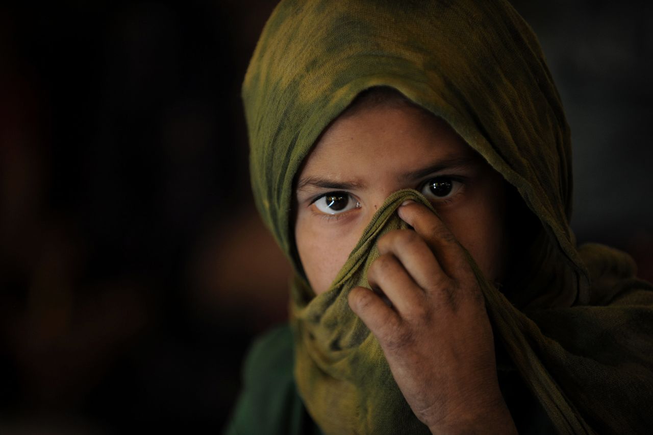 An Afghan Kuchi (Pashtun nomad) girl covers her face as she attends a class on October 27, 2010. She is being taught in a tent near the ruins of the Darul Aman Palace on the outskirts of Kabul.