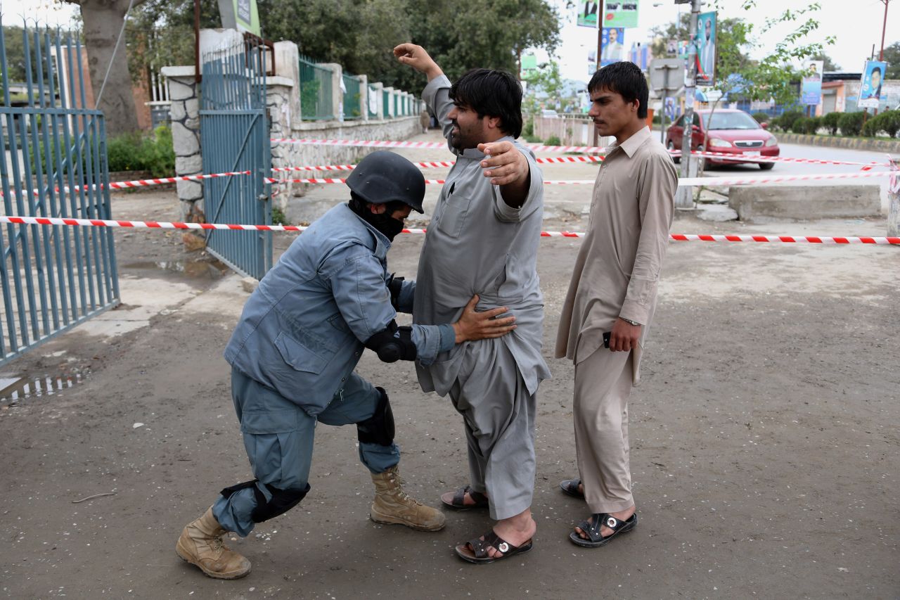 A police officer checks a man at a polling station in Jalalabad.