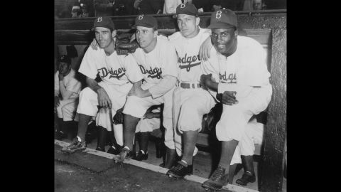 Jackie Robinson, who broke Major League Baseball's color barrier, poses in the dugout with some of his Brooklyn Dodgers teammates during his first game on April 15, 1947.
