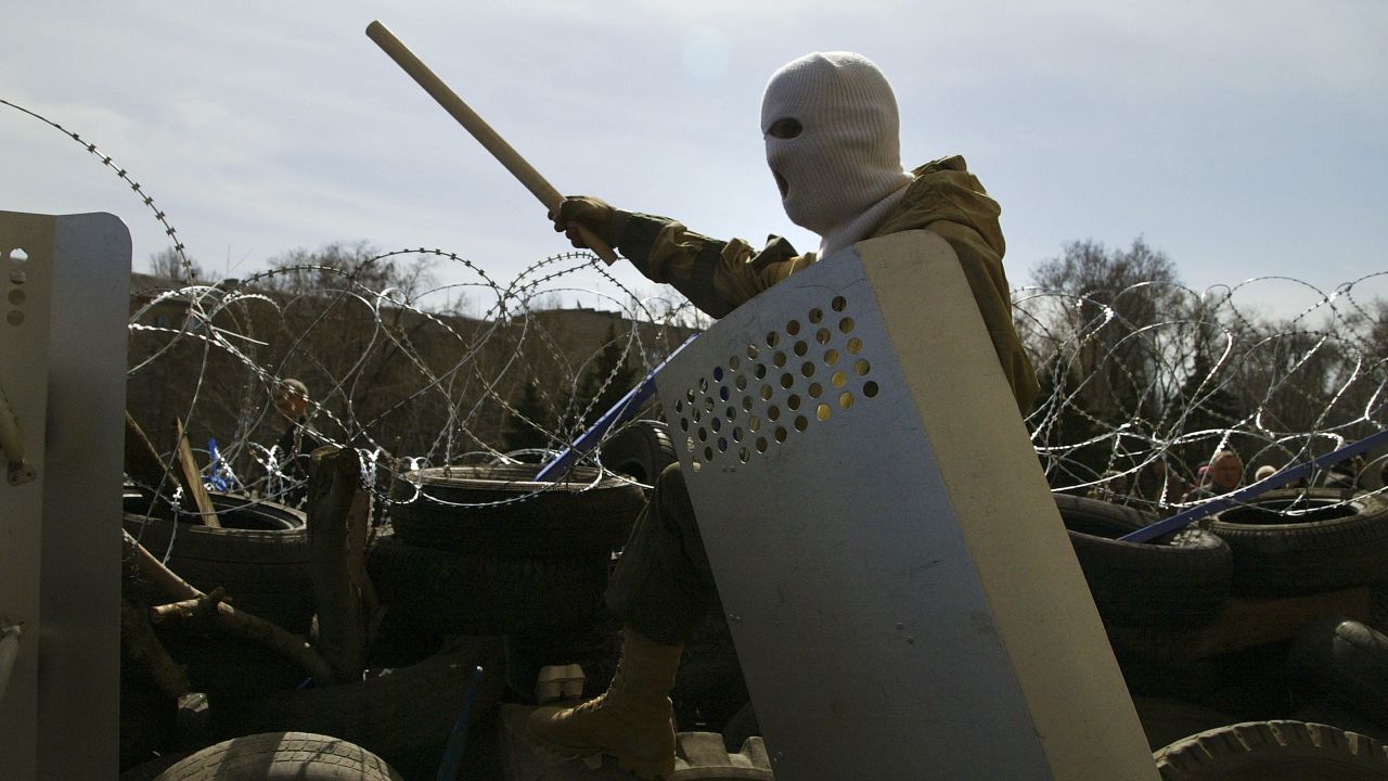 A masked man stands on top of a barricade at the regional administration building in Donetsk on April 7.
