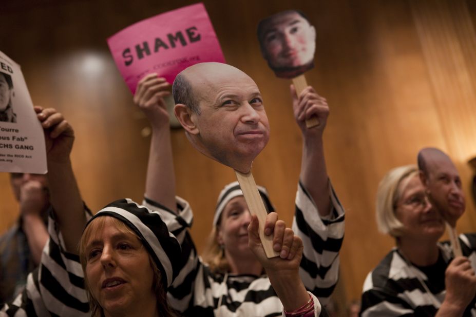 Today, the top 1% controls about 40% of national wealth. At a hearing in Washington D.C. about Wall Street and the financial crisis, protesters hold a placard depicting Goldman Sachs CEO Lloyd Blankfein, who once famously said, "I'm doing God's work."<br />
