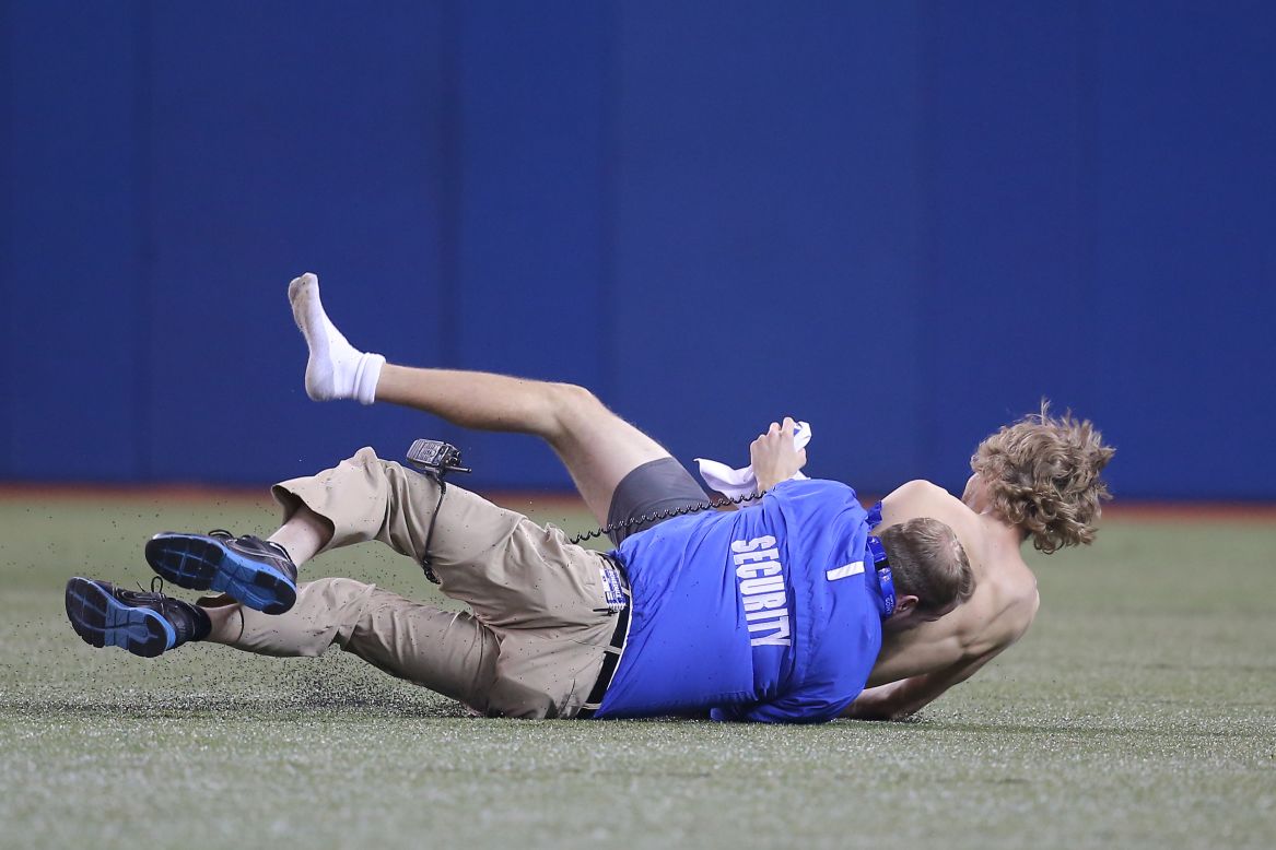 Security takes down a trespasser on the field during a Major League Baseball game in Toronto on Friday, April 4.