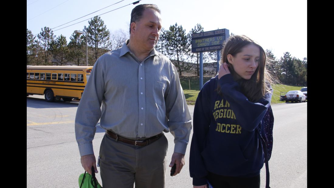 Jenna Mickel, a sophomore at Franklin Regional High School, stands with her father, Richard, as she talks to reporters outside the school on April 9.