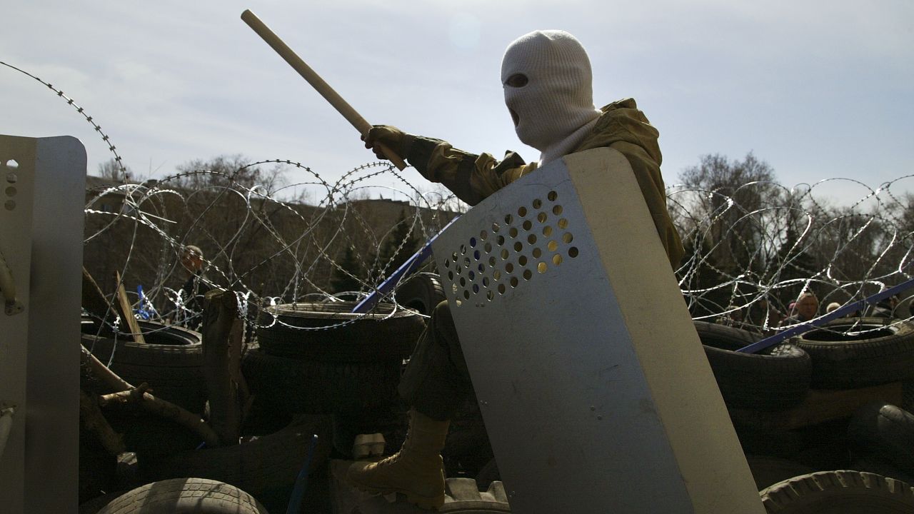 A masked man stands atop of a barricade at the regional administration building in in Donetsk, Ukraine, Monday, April 7, 2014.