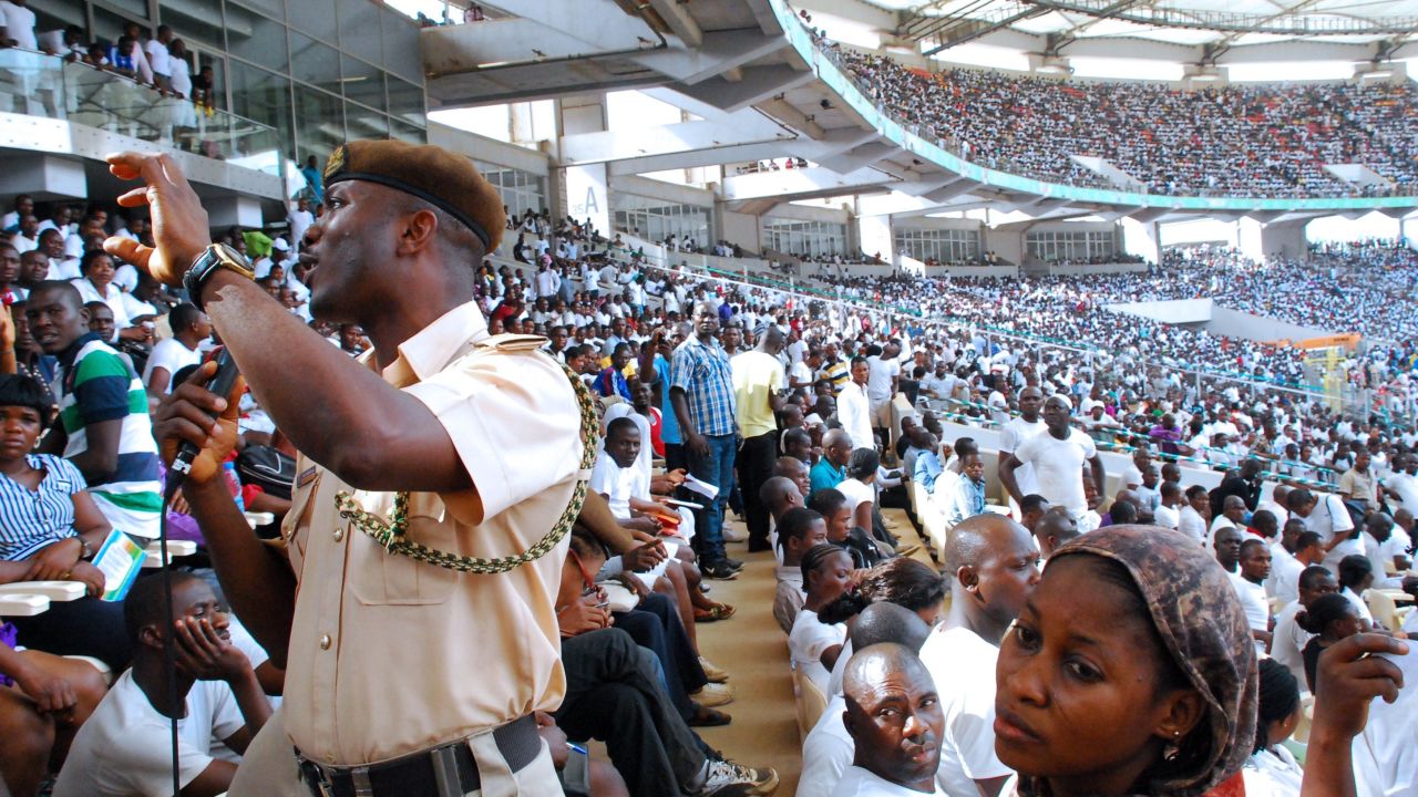A security agent speaks to job-seekers gathered in Abuja National Stadium to apply for work at the Nigerian immigration department on March 15, 2014. 