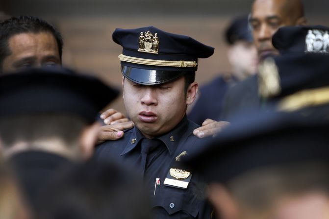 A police officer in New York City is comforted Wednesday, April 9, after a ceremony in honor of Officer Dennis Guerra. Guerra died Wednesday after he and his partner were injured responding to a fire.