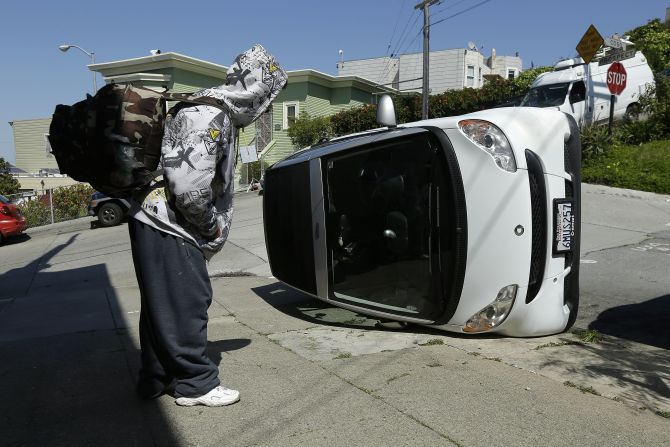A man looks at a tipped-over Smart car Monday, April 7, in San Francisco. Police said four Smart cars <a href="http://www.cnn.com/2014/04/08/us/smart-car-flipping-san-francisco/">were flipped over</a> in an apparent early morning vandalism spree. 
