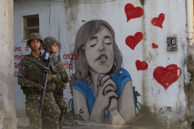 Soldiers stand next to graffiti in Complexo da Mare, one of the largest favela complexes in Rio de Janeiro, on Saturday, April 5. The Brazilian government has deployed federal forces to violence-plagued slums ahead of the FIFA World Cup, which starts in June. 