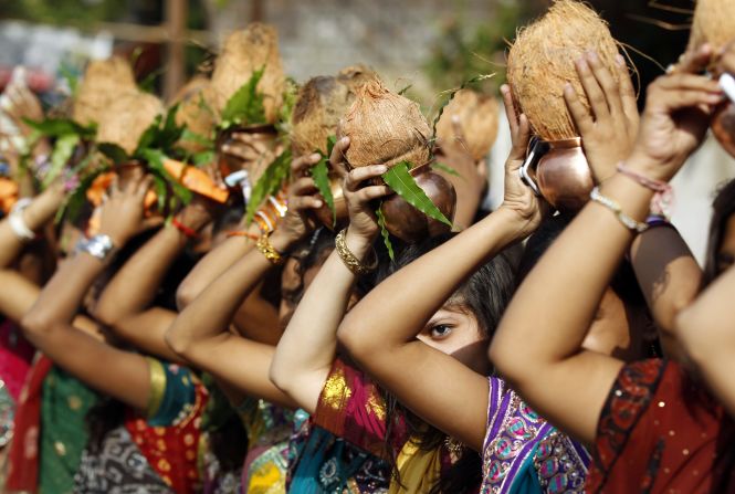 Women in Vadodara, India, hold copper pots and coconuts over their heads on Wednesday, April 9, to give a traditional welcome to Narendra Modi, a candidate running for prime minister.