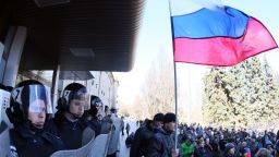 A man holds a Russian flag as police officers stand guard outside the regional government administration building in the center of the eastern Ukrainian city of Donetsk during a rally of pro-Russia supporters on April 5, 2014.